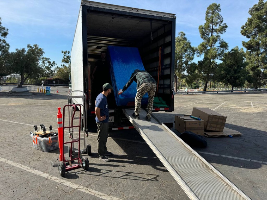 Team loading protected furniture up a truck ramp